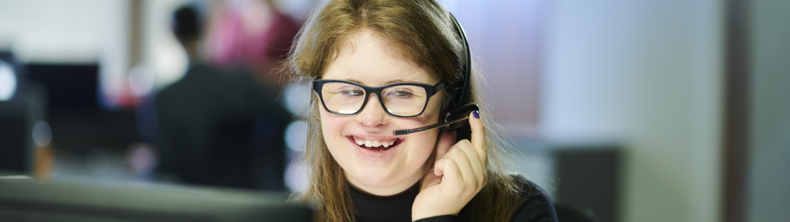 young woman with Down syndrome similing while taking a call at work